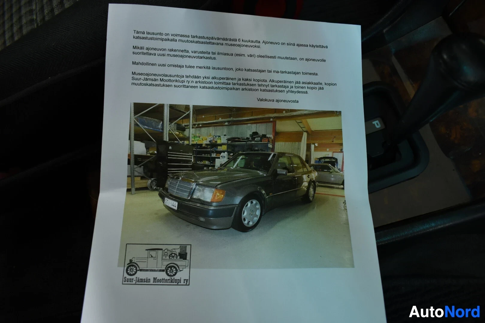 Asiakirja: Dokumentti, jossa on tekstiä ja kuva autosta, jonka keula on kuvaajasta poispäin.