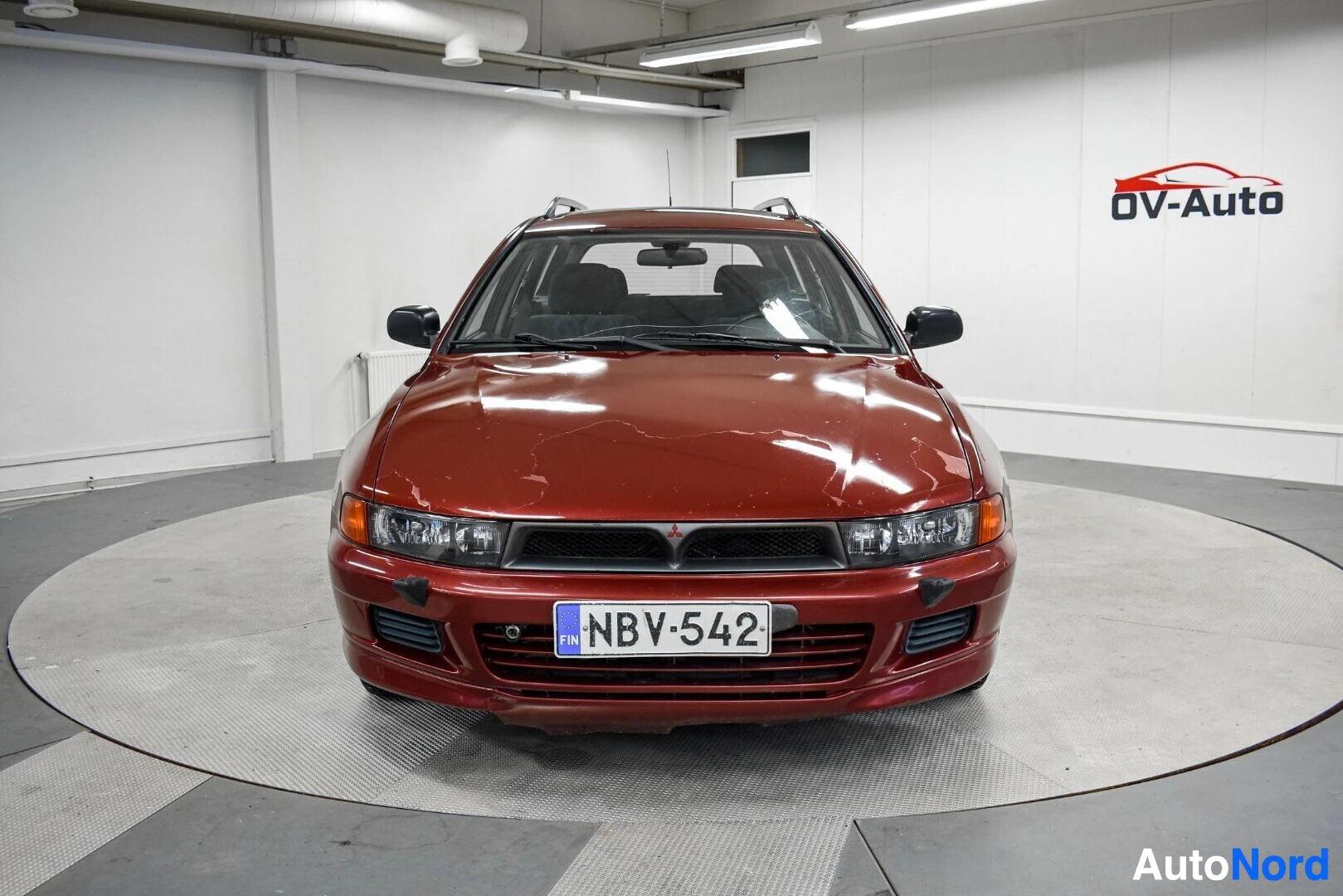 Edestä: Punainen Mitsubishi Galant farmariauto kuvattuna suoraan edestä. Autossa on rekisterikilpi