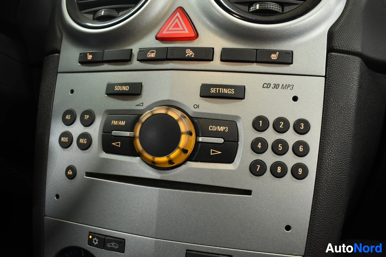 Yksityiskohta: Lähikuva auton keskikonsolin yläosasta, jossa on CD 30 MP3 -radio, hätävilkkupainike ja istuinlämmittimien painikkeet.