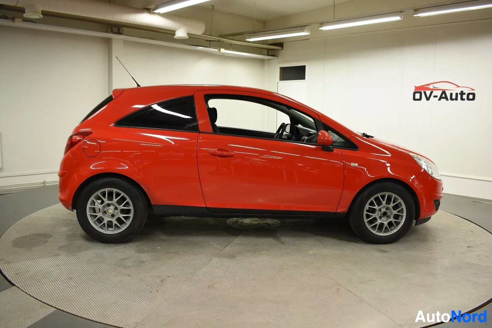 Sivulta: Punainen kaksiovecorsoinen auto kuvattuna sivulta. Autossa on hopeanväriset vanteet.