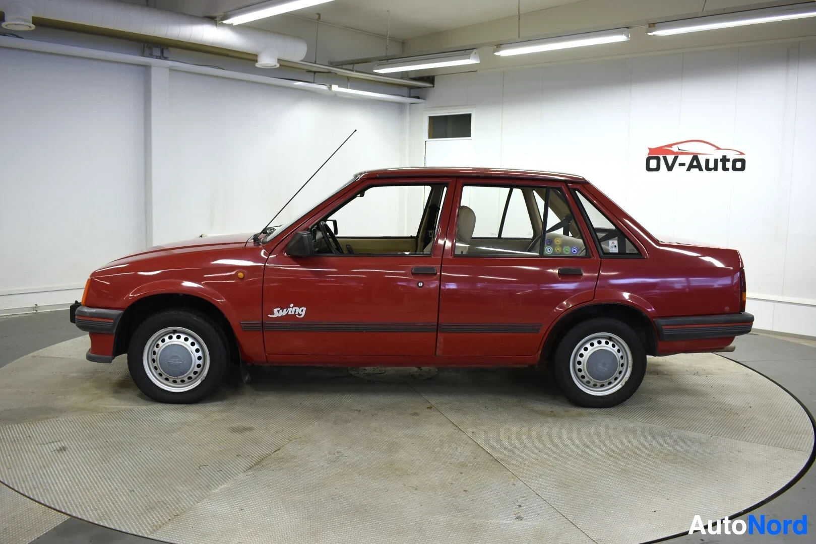 Sivulta: Punainen Opel Corsa -henkilöauto vasemmalta sivulta kuvattuna. Autossa on neljä ovea, mustat kylkilistat ja harmaat pölykapselit. Kyljessä näkyy "Swing"-teksti.