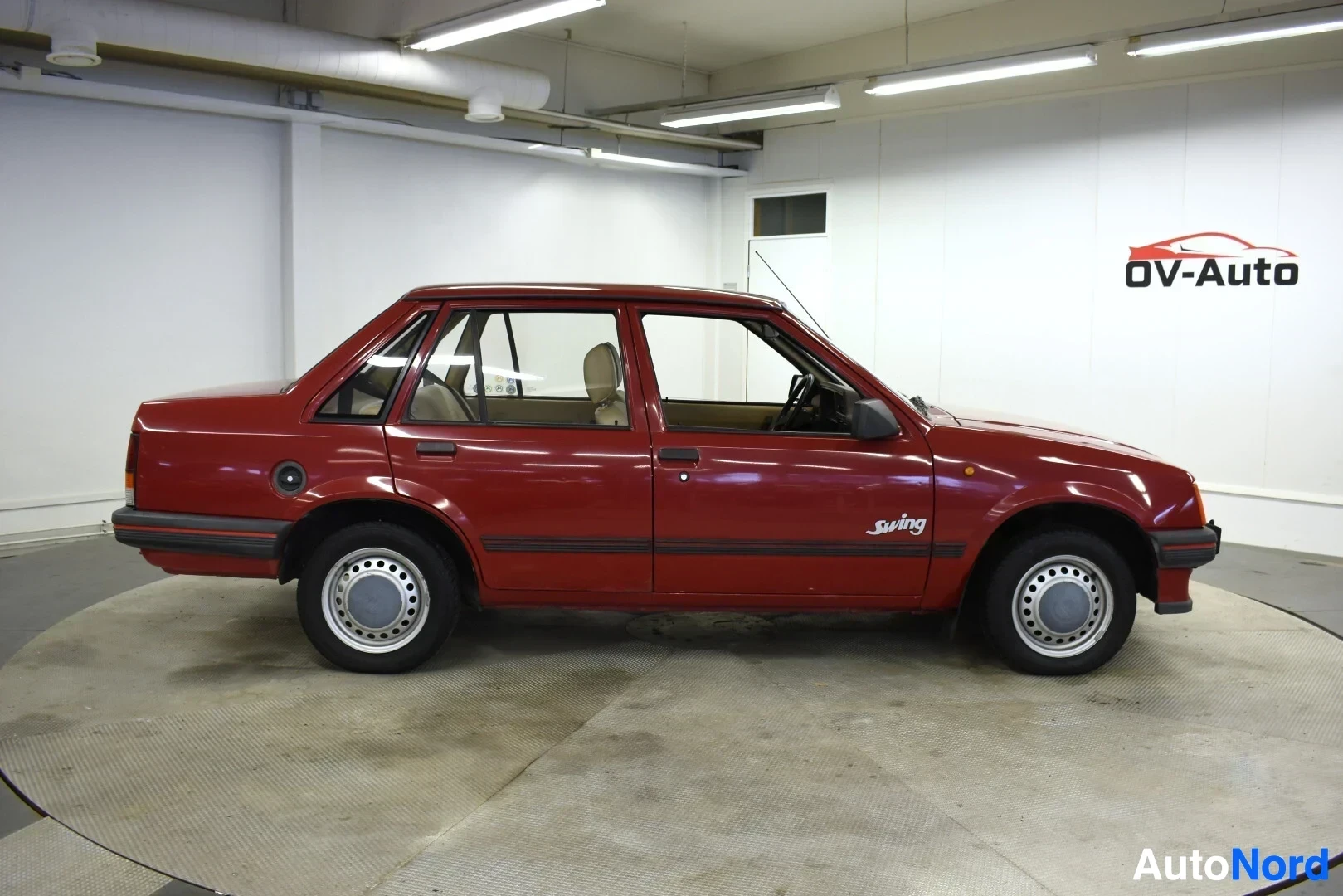 Sivulta: Punainen henkilöauto kuvattuna vasemmalta sivulta. Oikea sivupeili näkyy osittain. Auton kyljessä, etuoven ja takaoven alaosassa on "Swing"-merkintä. Vanteet ov
