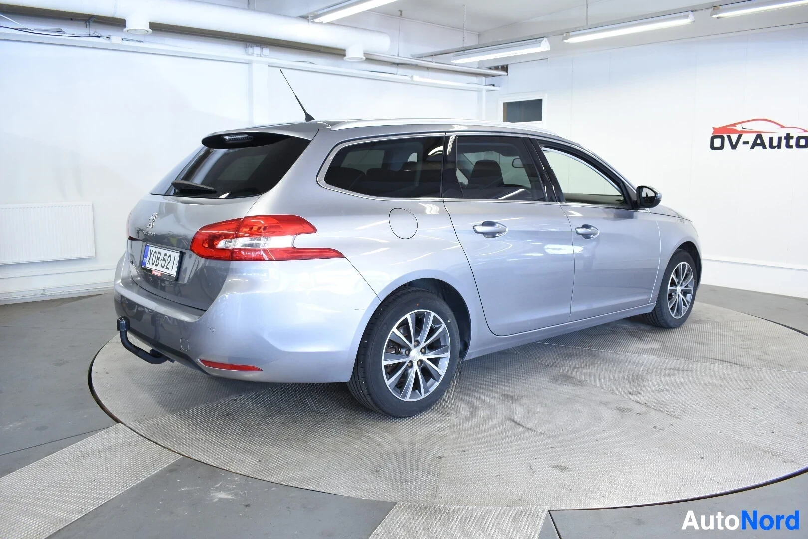 Takaviisto: Hopeanvärinen Peugeot 308 SW takaviistosta vasemmalta kuvattuna. Ajoneuvossa on vetokoukku ja kattokiskot.