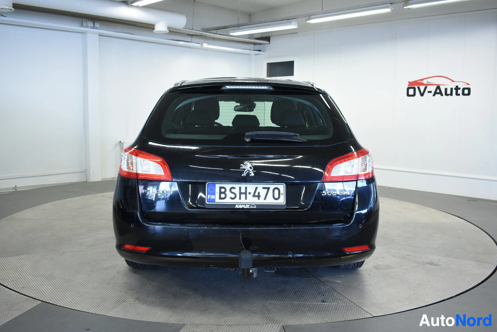 Takaa: Musta farmariauto kuvattuna suoraan takaa. Autossa on vetokoukku ja rekisterikilpi
