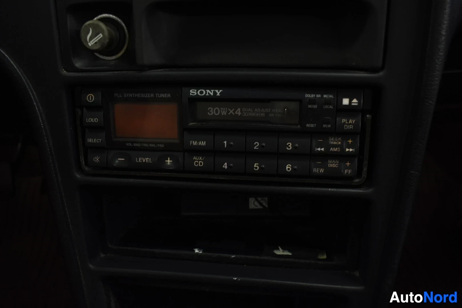 Ohjaamo: Lähikuva SONY-merkkisestä autoradion soittimesta ja tuhkakupista kojelaudan keskiosassa.