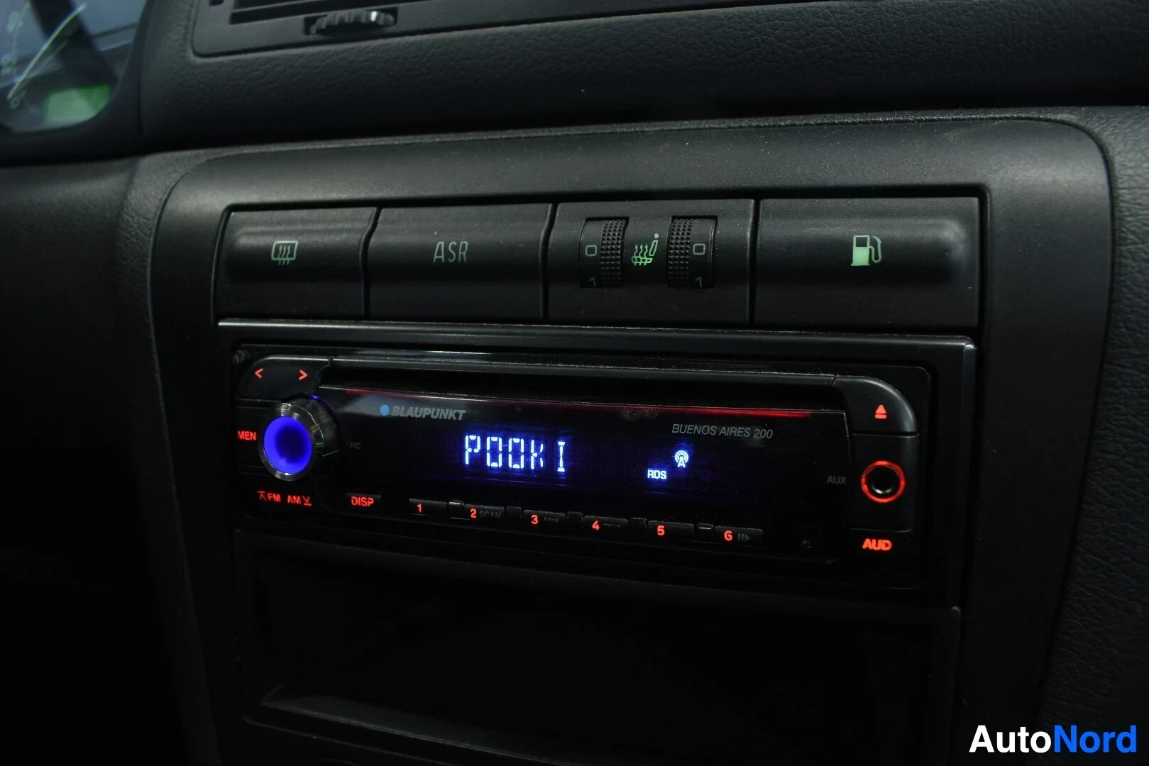 Yksityiskohta: Lähikuva kojelaudan keskiosasta, jossa on Blaupunkt Buenos Aires 200 -radio, puhaltimen ohjaimet ja ASR-painike.