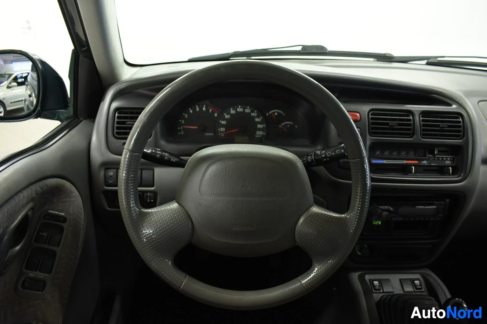 Yksityiskohta: Ohjauspyörä, jossa on keskiössä "AIRBAG"-merkintä. Sen takana näkyvät mittaristo sekä ilmanvaihtoaukot ja radio.