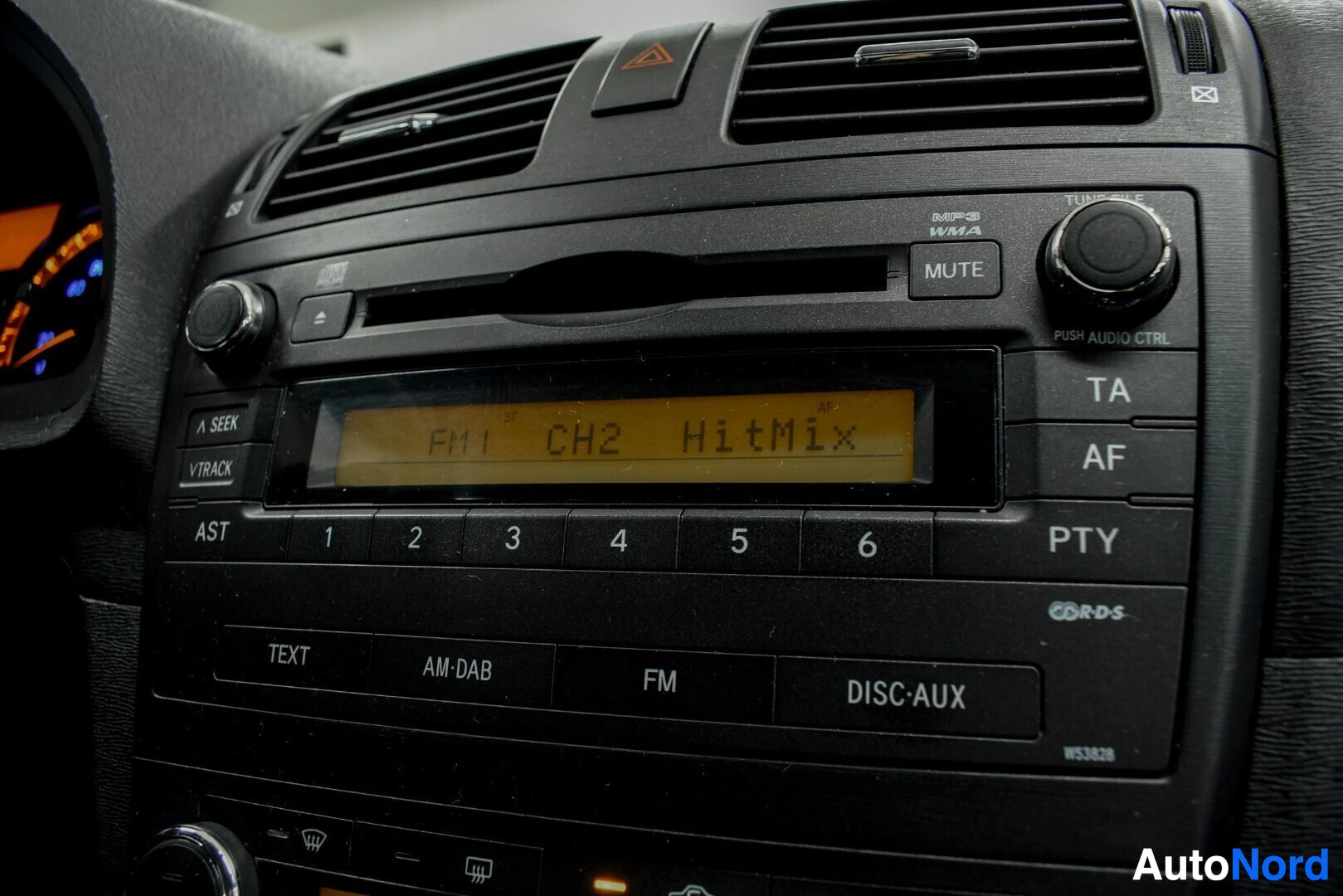 Yksityiskohta: Lähikuva auton keskusnäytöstä ja radiopaneelista. Näytöllä lukee "FM1 CH2 HitMix".