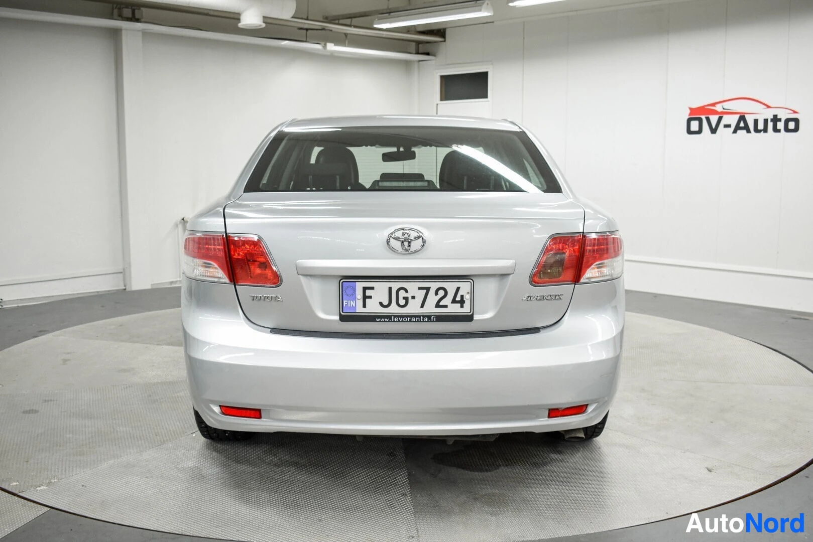 Takaa: Hopeanvärinen sedan-tyyppinen henkilöauto on kuvattu suoraan takaa. Auton takaluukussa on rekisterikilpi FJ G-724.