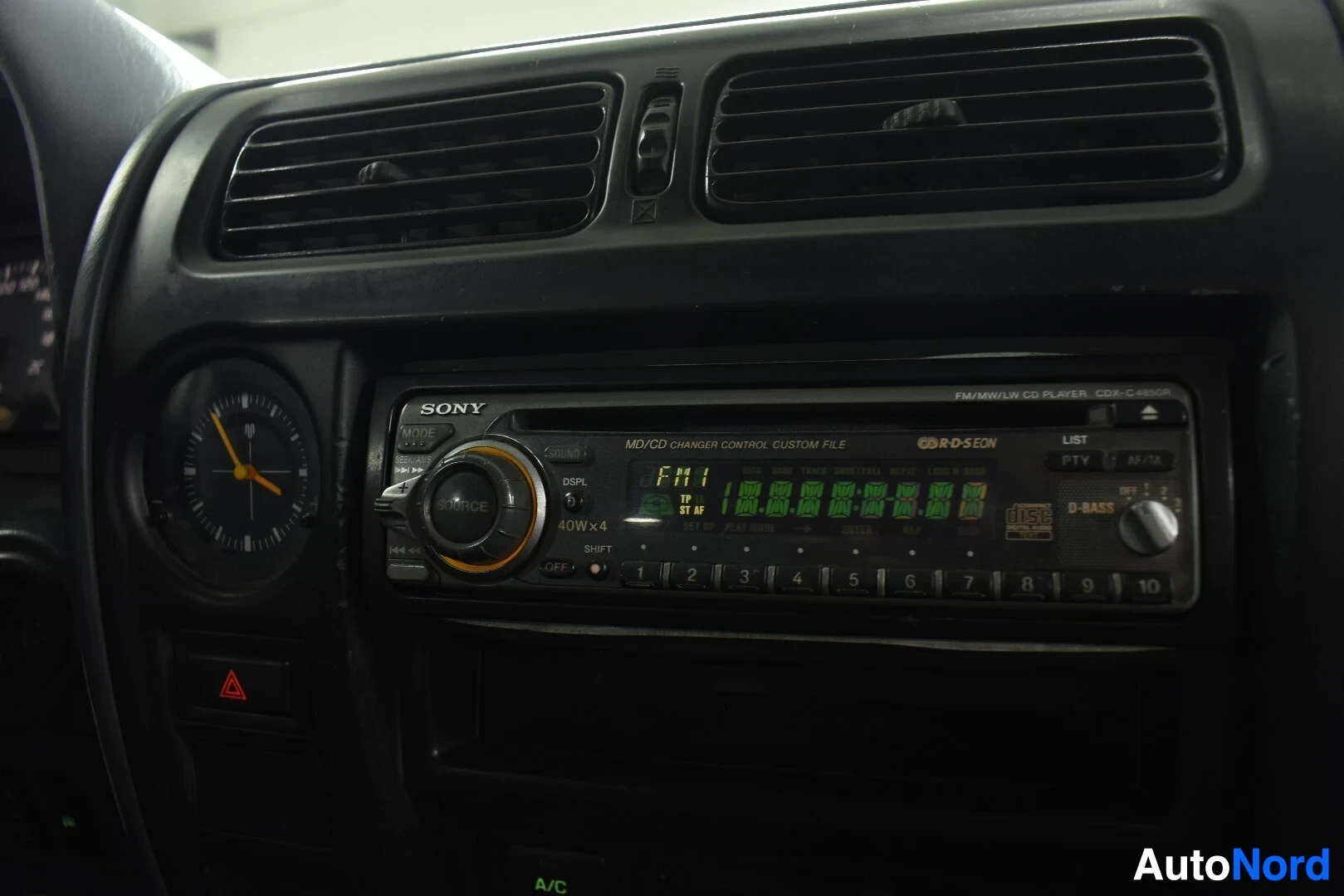 Yksityiskohta: Lähikuva kojelaudan keskiosasta, jossa näkyy analoginen kello ja Sony-merkkinen FM/MD/CD-soitin CDX-C480R-mallimerkinnällä.