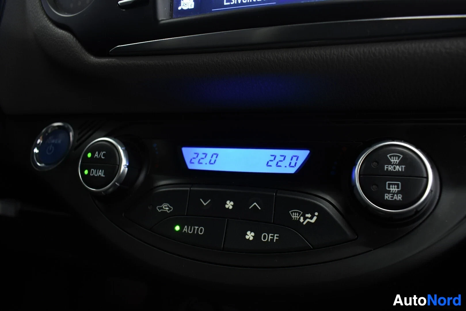 Yksityiskohta: Lähikuva auton ilmastointisäätimistä. Näytöissä lukee "22.0" ja "DUAL", "AUTO" ja "OFF" -painikkeet näkyvät.