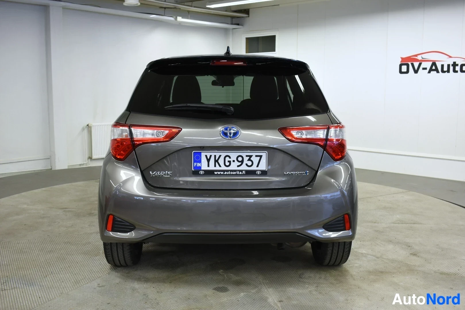 Takaa: Auton takaosa kuvattuna suoraan takaa. Rekisterikilvessä on teksti. Takavalot ja takaluukun hybrid-logo ovat selvästi näkyvissä. Oikealla takapuskurin a