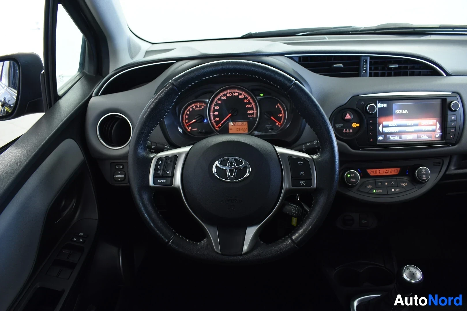 Ohjaamo: Kojelauta ja ohjauspyörä, jossa on Toyota-logo. Mittaristossa näkyy 121303 km lukema. Keskikonsolissa on näyttö ja ilmastoinnin säätimet.