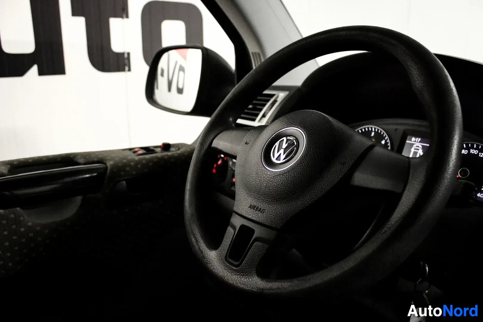 Yksityiskohta: Auton ohjauspyörä ja mittaristo kuljettajan puolelta kuvattuna. Ohjauspyörässä on Volkswagen-logo ja airbag-teksti.