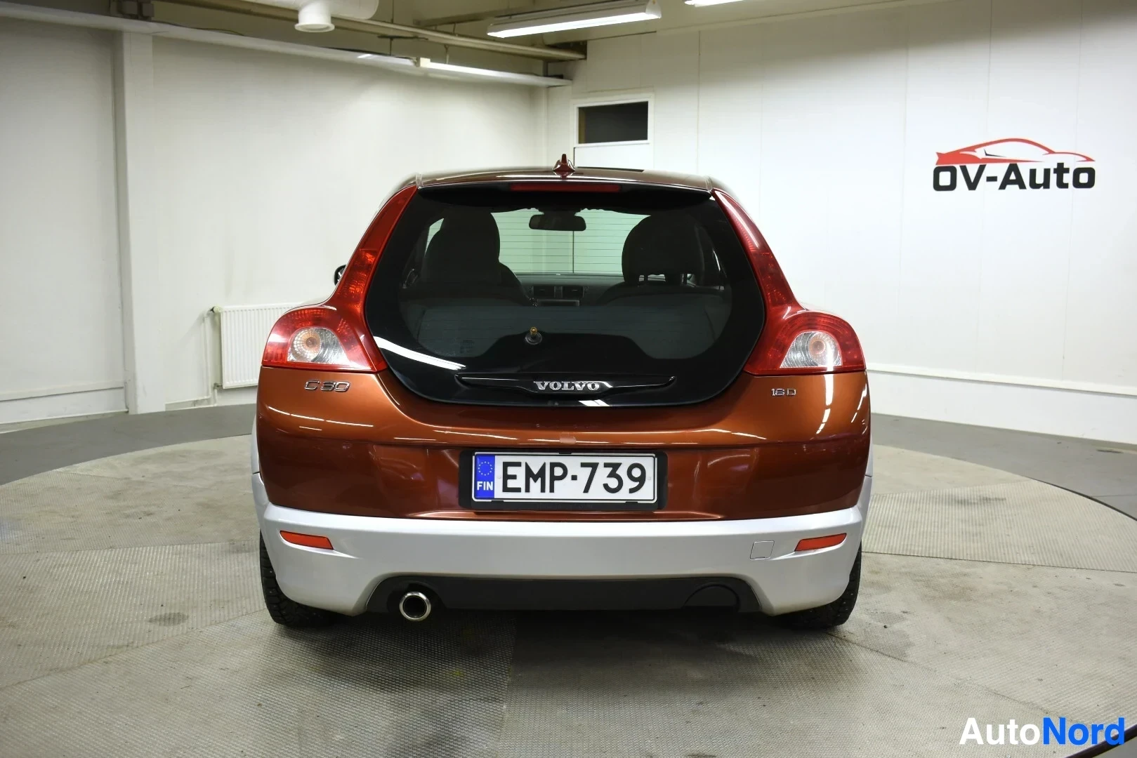 Takaa: Volvo C30 -henkilöauto kuvattuna suoraan takaa. Näkyvissä on takaluukku, takapuskuri ja pakoputki. Rekisterikilpi on asennettuna. Takalasin alareunassa