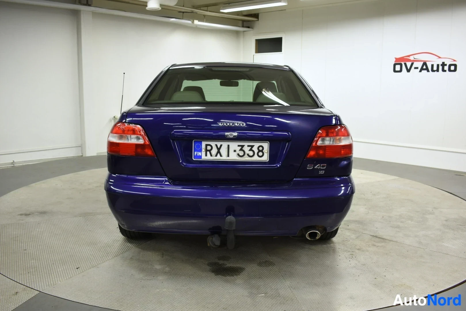 Takaa: Sininen sedan-tyyppinen henkilöauto kuvattuna takaa. Autossa on vetokoukku.
