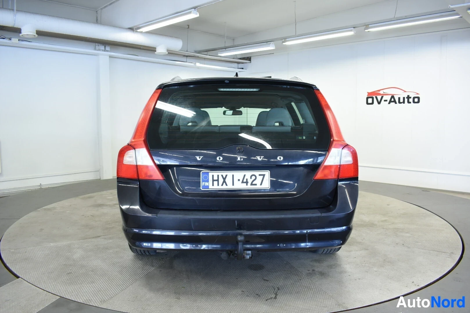 Takaa: Musta Volvo V70 -farmariauto takaa kuvattuna sisätiloissa. Autossa on vetokoukku.
