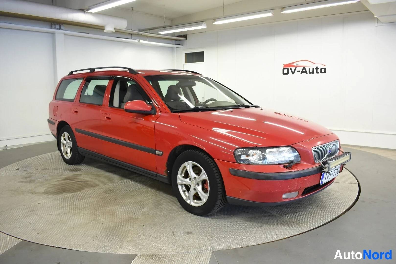 Etuviisto, nokka oikealle: Punainen Volvo V70 -farmariauto kuvattuna etuoikealta.
