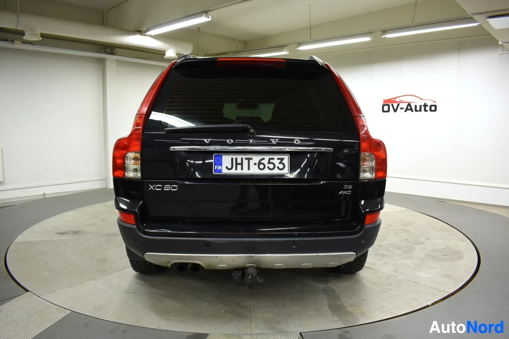 Takaa: Mustan Volvo XC90:n takaosa, jossa on rekisterikilpi "" ja vetokoukku. Takaluukussa näkyy "XC90" ja "D5 AWD" -merkinnät