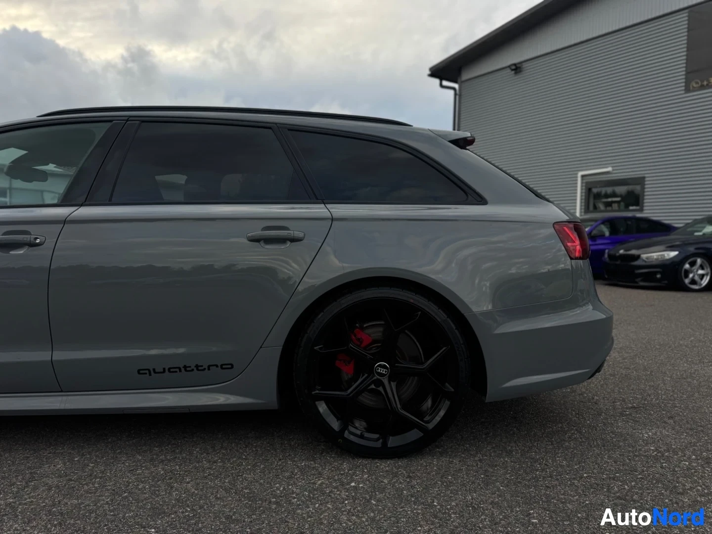 Takaviisto: Harmaa farmariauto kuvattuna oikeasta takakulmasta. Autossa on mustat kattokaiteet ja tummennetut takasivuikkunat. Takaoven alaosassa lukee "quattro". Pyörässä