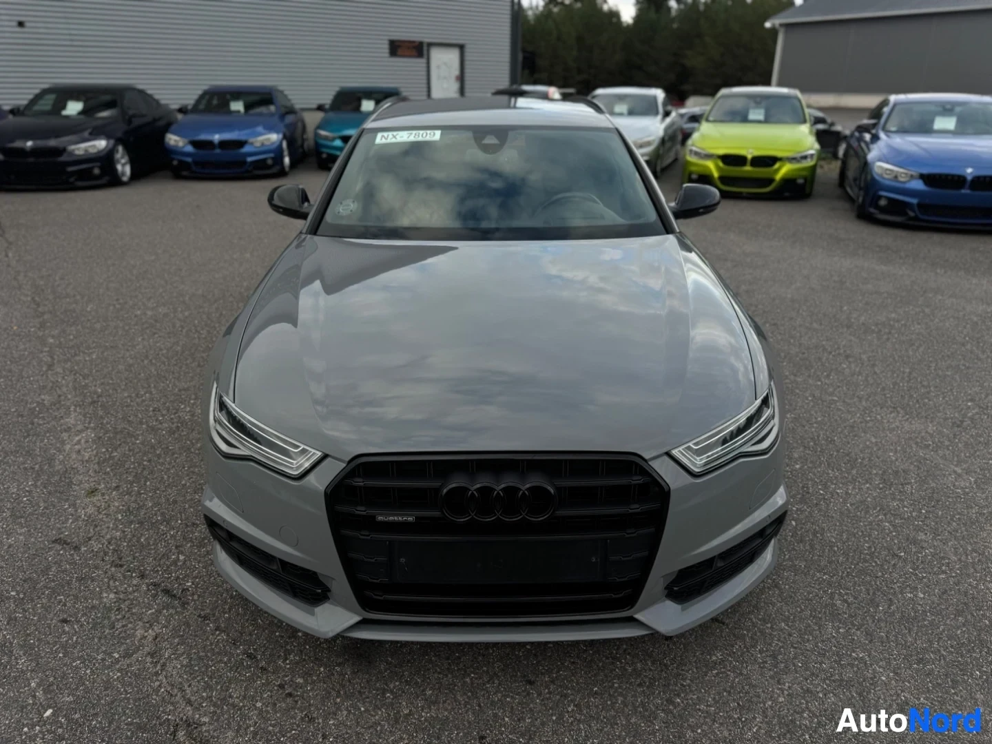 Edestä: Harmaa farmariauto edestä kuvattuna. Tuulilasissa on tarra, jossa lukee "NX-7809".