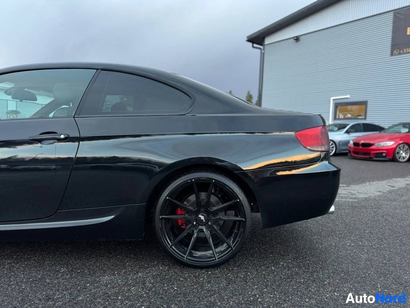 Takaviisto: Mustan coupé-auton takaosa ja kylki matalasta kuvakulmasta. Auton takarengas ja jarrusatula ovat näkyvissä.
