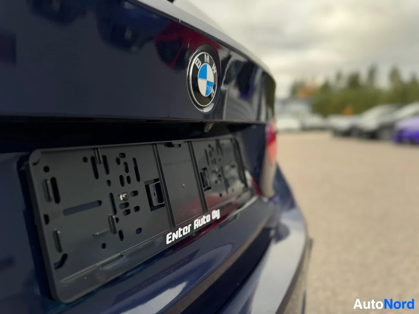 Takaa: Lähikuva tummansinisen auton takaosasta, jossa näkyy BMW-logo ja tyhjä rekisterikilven kehys tekstillä "Enter Auto Oy".