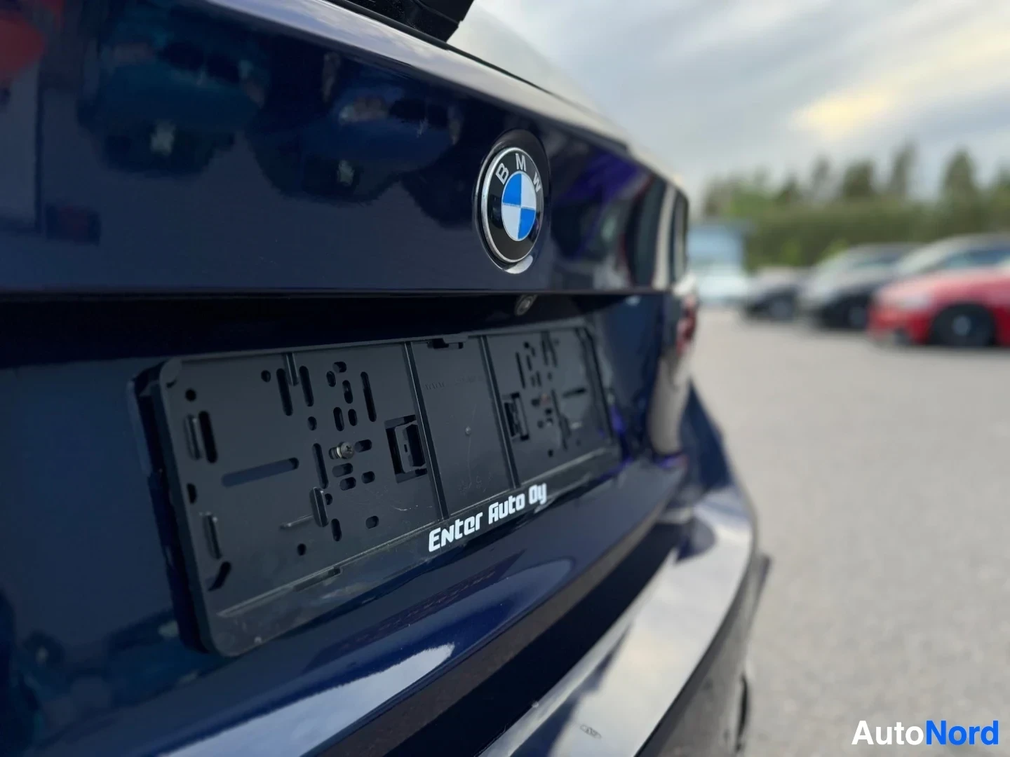 Yksityiskohta: Lähikuva tummansinisen auton takaosasta, jossa näkyy BMW-logo ja rekisterikilven kehys tekstillä "Enter Auto Oy".