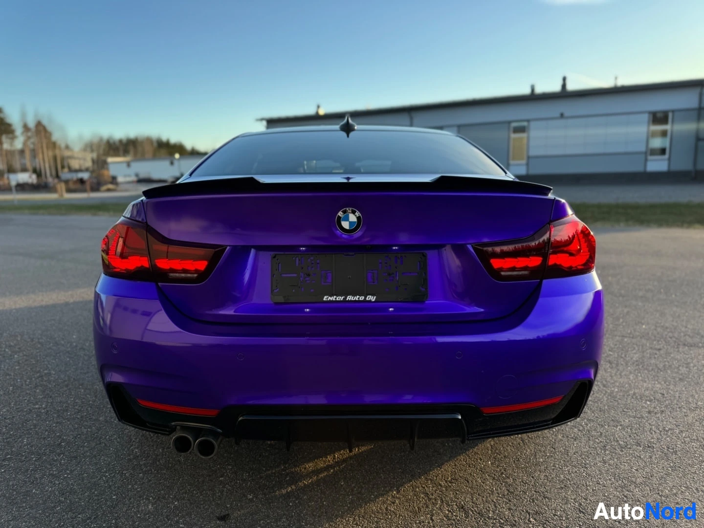 Takaa: Violetti coupé-auto suoraan takaa kuvattuna ulkona. Auton rekisterikilven paikalla on musta kehys, jossa lukee "Enter Auto Oy". Takavaloissa on yhtenäiset LED-v