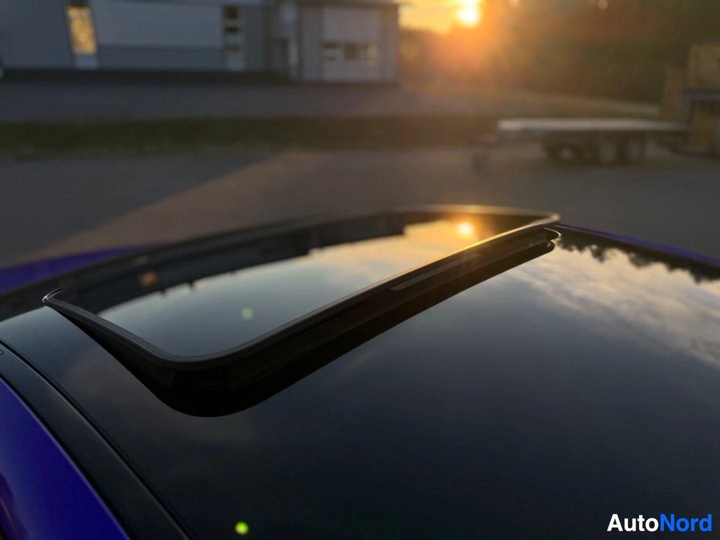 Yksityiskohta: Violetin auton katolla oleva avoin lasinen kattoluukku ilta-auringon paisteessa.