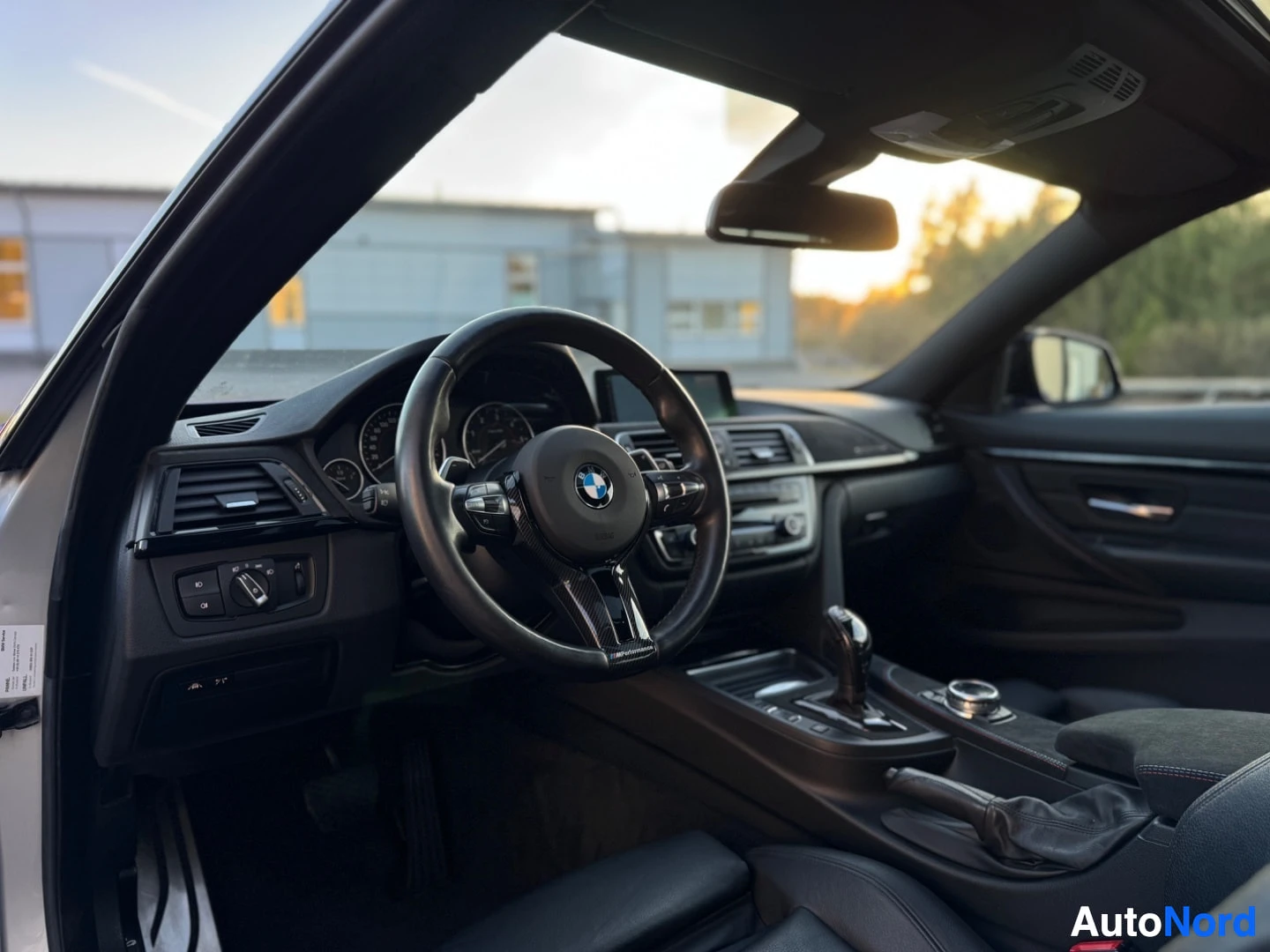 Ohjaamo: Kuvassa näkyy auton ohjauspyörä, kojelauta ja keskikonsoli. BMW-logo on ohjauspyörän keskellä.
