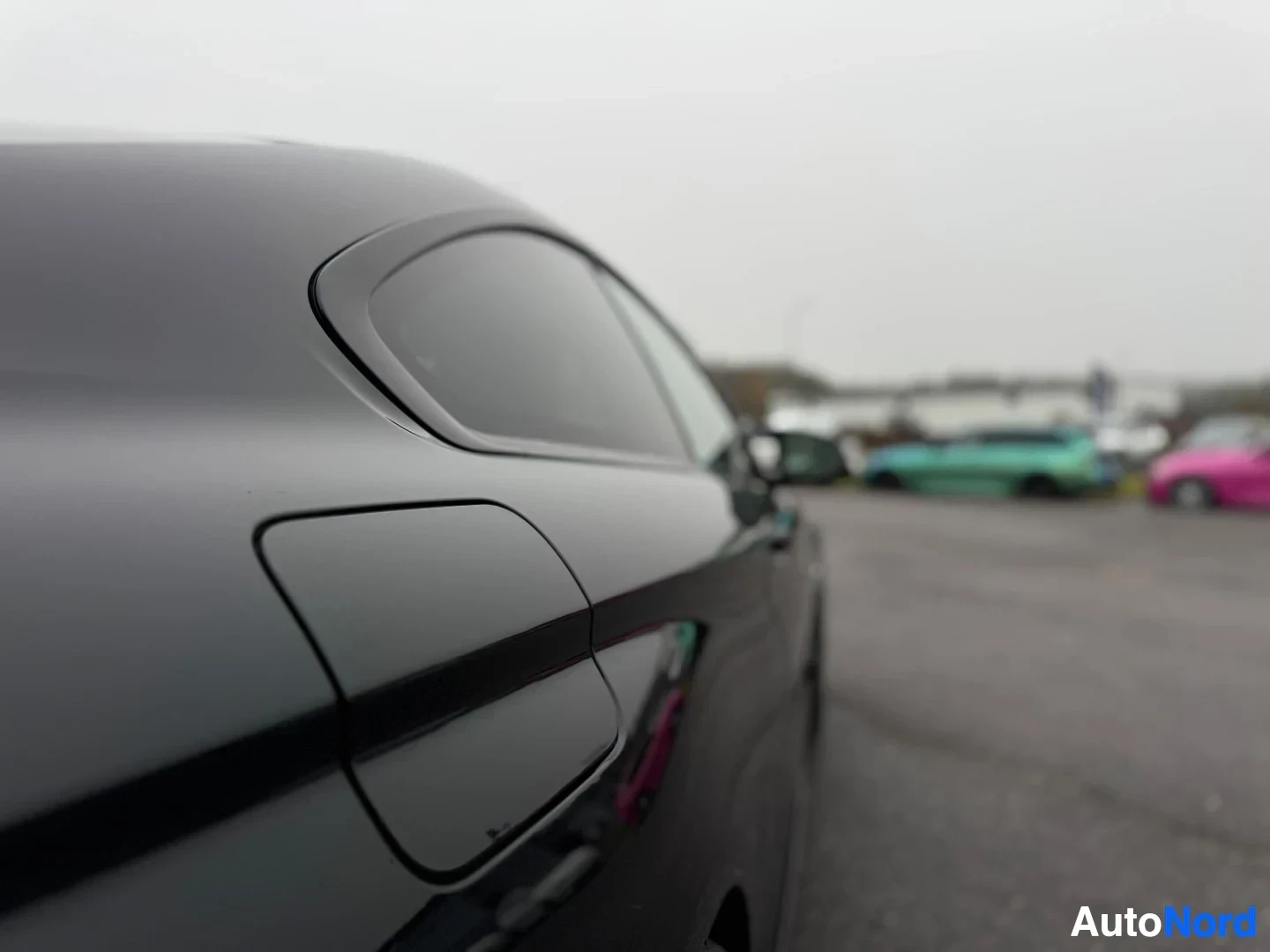 Yksityiskohta: Lähikuva mustan auton takaosasta, jossa näkyy takaikkuna ja polttoainetankin luukku, auto on pysäköitynä ulos.