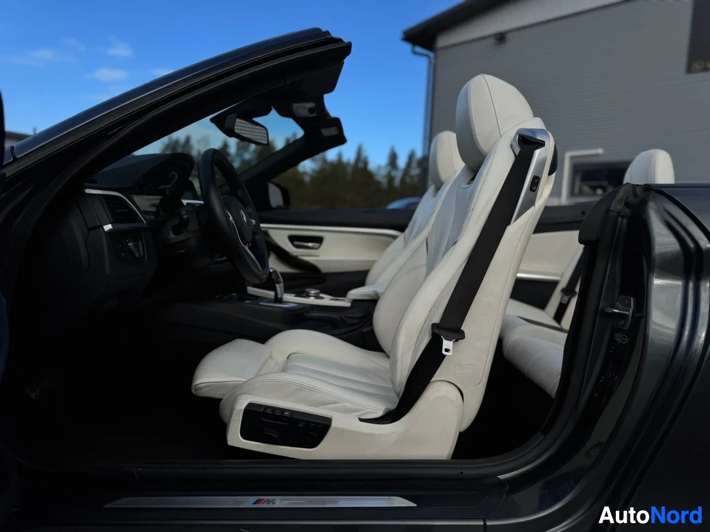 Ohjaamo: Auton ohjaamo kuvattuna oikeasta etukulmasta, mustassa autossa on vaaleat nahkaistuimet.