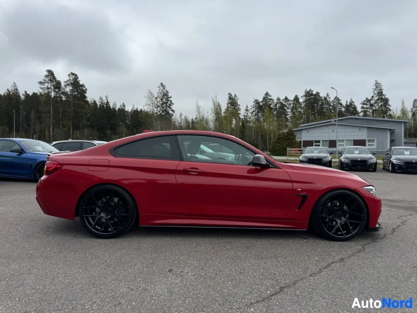 Sivulta: Punainen coupé-auto parkkipaikalla, sivusta kuvattuna. Auton vasen kylki näkyy kokonaisuudessaan.