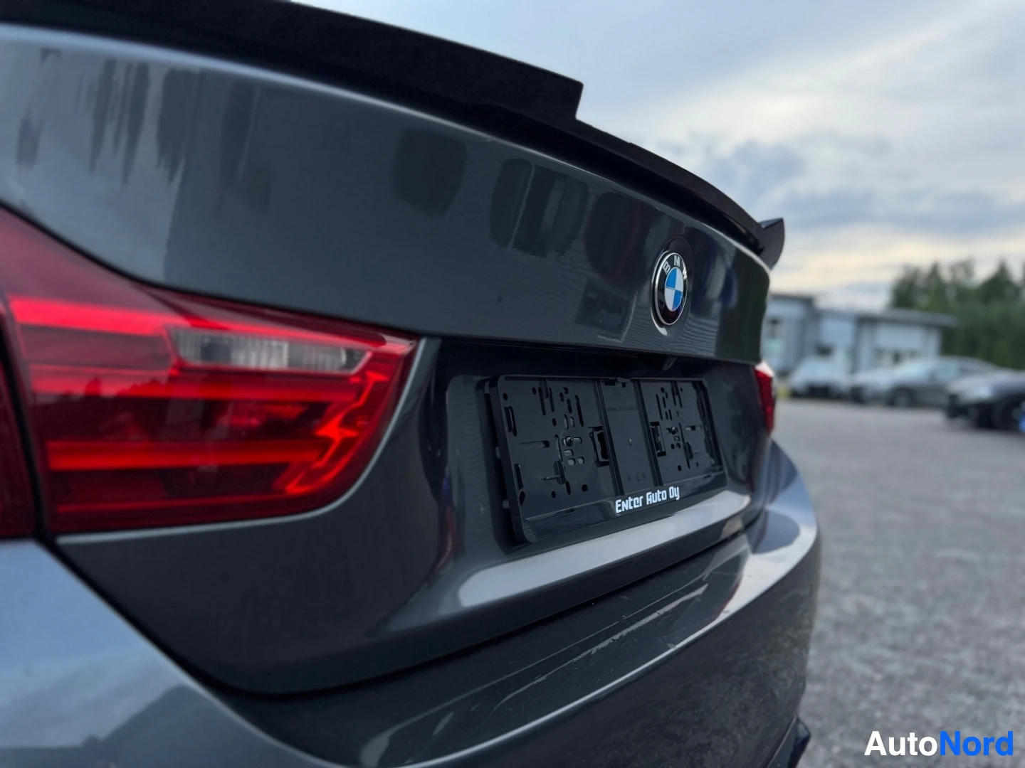 Takaviisto: Auton takaosan vinokuvassa näkyvät BMW-logo, kilpiteline ja osa takavalosta. Kilpitelineessä lukee "Enter Auto Oy".