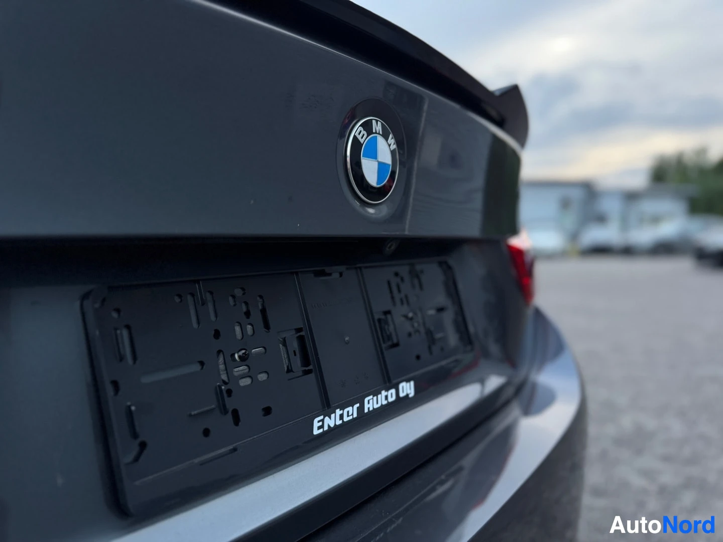 Takaviisto: Lähikuva auton takaosasta, jossa näkyvät BMW-logo ja kilpiteline. Kilpitelineessä lukee "ENter Auto Oy".