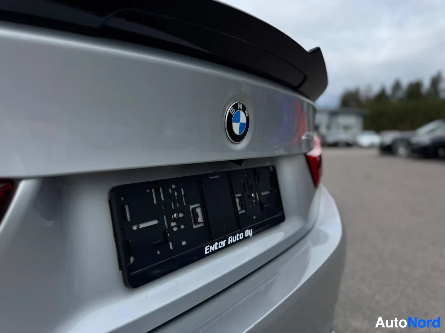 Takaviisto: Auton takaosan lähikuva, jossa näkyy BMW-logo, rekisterikilven kehys ja takaluukku.