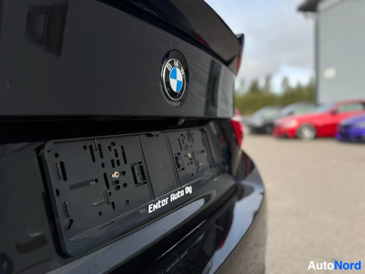 Takaa: Lähikuva auton takaosasta, jossa näkyy takaluukun BMW-logo ja tyhjät rekisterikilven kehykset, joissa lukee "Enter Auto Oy".