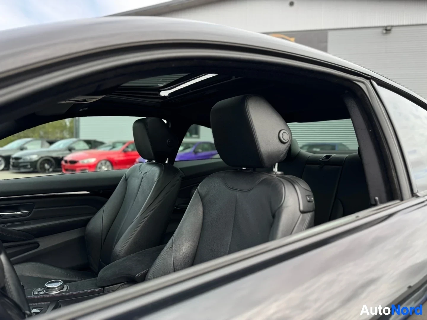 Ohjaamo: Mustan auton musta sisätila, näkymä matkustajan puolelta eteenpäin. Mustat nahkaiset etuistuimet ja takapenkit ovat näkyvissä. Katossa on avattu kattoluukku.
