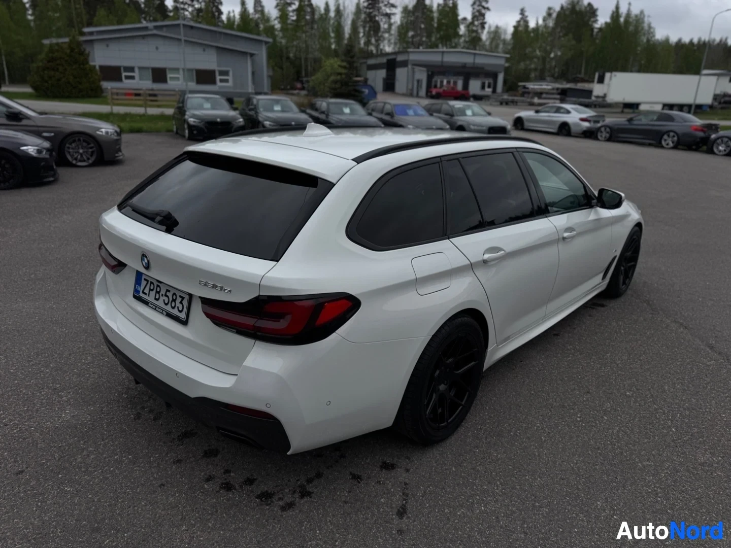 Takaviisto: Valkoinen farmariauto pysäköitynä, kuvattuna takaoikealta viistosta. Näkyvissä ovat kattokiskot ja tummat ikkunat.