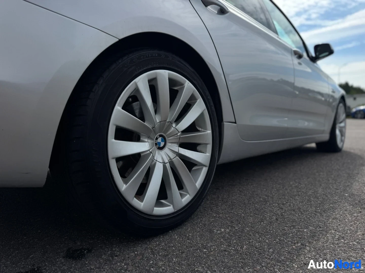 Takaviisto: Kuva auton takaosan vasemmasta kyljestä ja takapyörästä. Vasen takaovi ja takalokasuoja näkyvät. Vanteessa on BMW-logo. Renkaan kyljessä lukee "OUTSIDE" ja "245