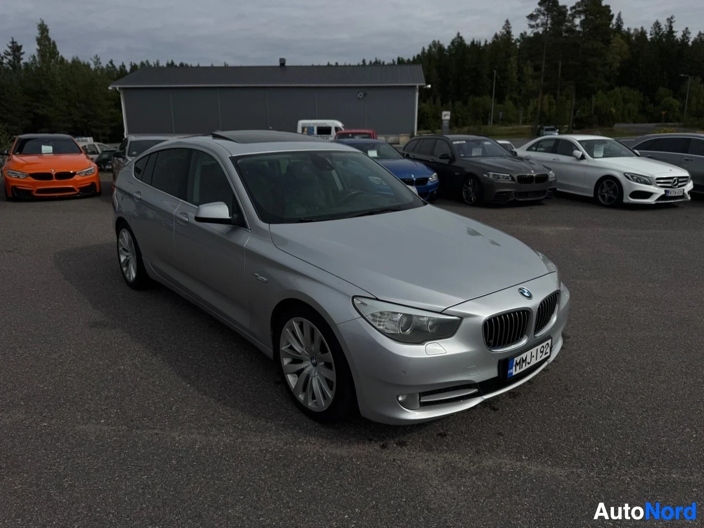 Etuviisto, nokka vasemmalle: Hopeanvärinen henkilöauto edestä oikealta puolelta, etupuskurin vasemmassa reunassa pysäköintitutka-anturi. Ajoneuvo on pysäköity asfaltille autoliikke