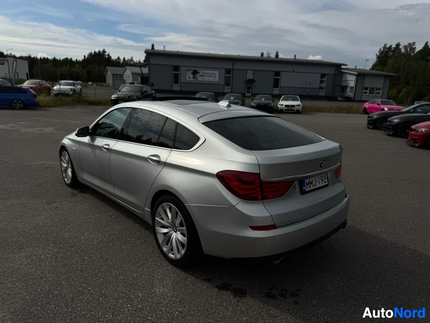 Takaviisto: Hopeanvärinen henkilöauto parkkipaikalla, takaosa ja oikea kylki näkyvissä. Auton takarekisterikilvessä lukee. Ajoneuvon takapuskurissa on parkkitutkan