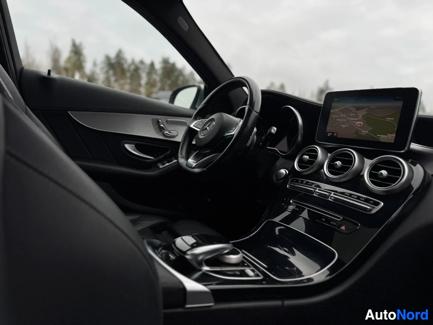 Ohjaamo: Kuvassa näkyy auton sisätilat, vasemmanpuoleisen etuistuimen selkänoja etualalla ja kojelauta keskellä. Ohjauspyörä, jossa on Mercedes-Benz-logo, sekä keskikons