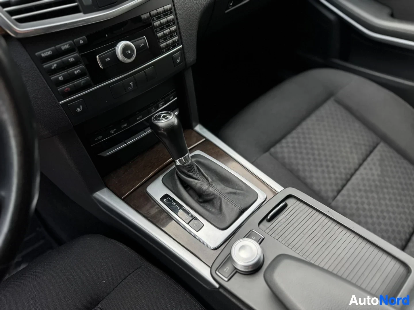 Ohjaamo: Kuva auton sisätiloista näyttää keskikonsolin, vaihdekepin, median säätimet ja etupenkit. Konsolissa on puunsyytä jäljittelevä koristelista.