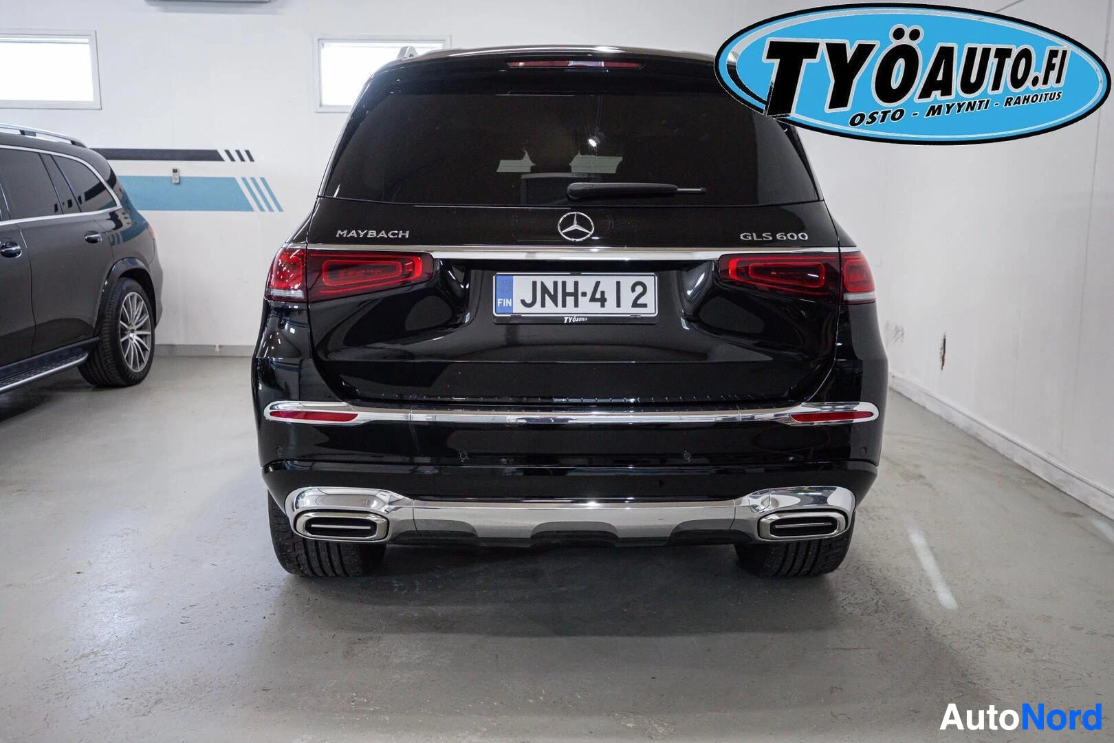 Takaa: Musta katumaasturi, jossa on Maybach- ja GLS 600 -merkit, pysäköitynä sisätilaan, takaosa näkyvissä.