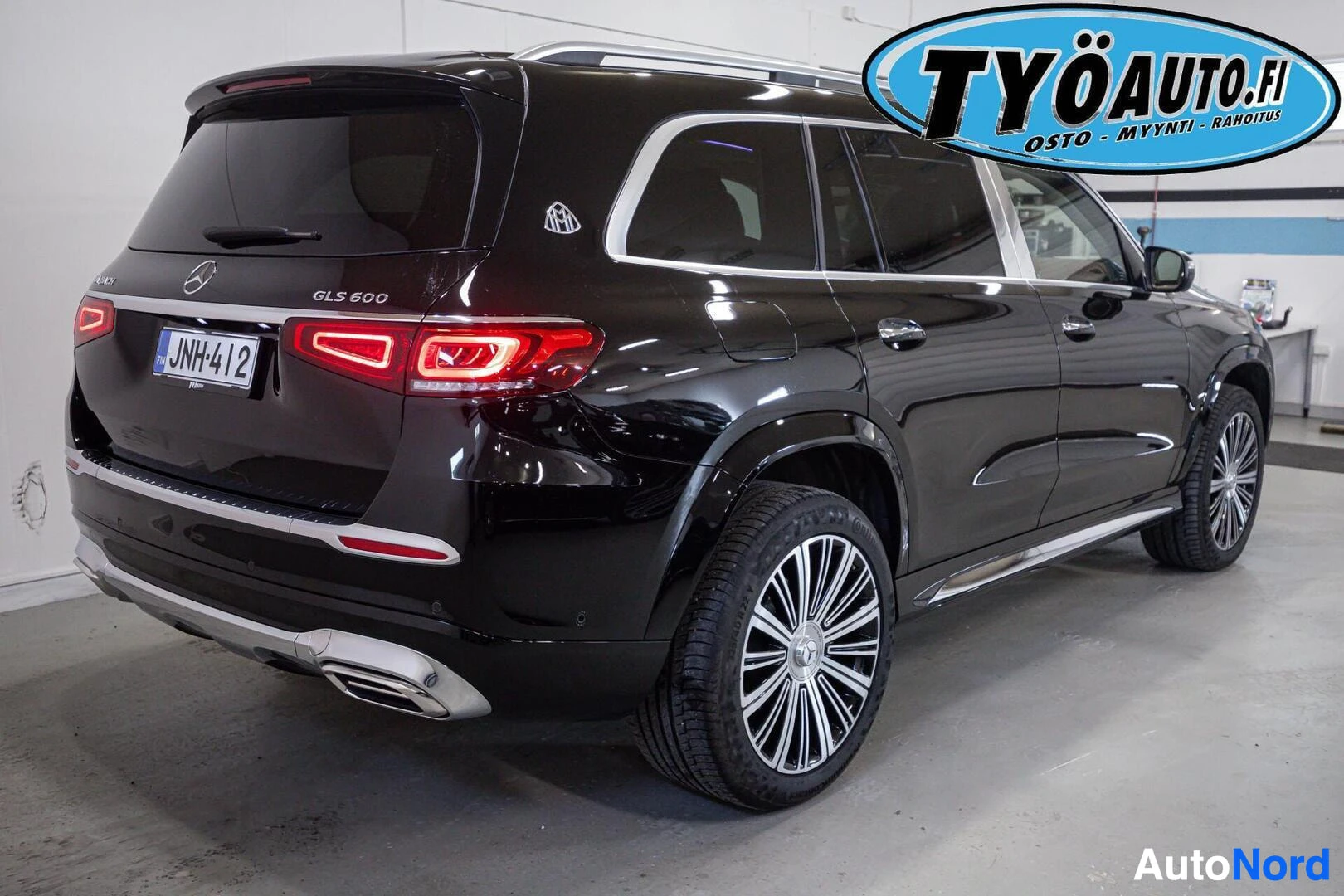 Takaviisto: Musta katumaasturi, jossa on Maybach- ja GLS 600 -merkit sekä kromikoristeita, pysäköitynä valkoiseen tilaan, oikeanpuoleinen takakulma näkyvissä.