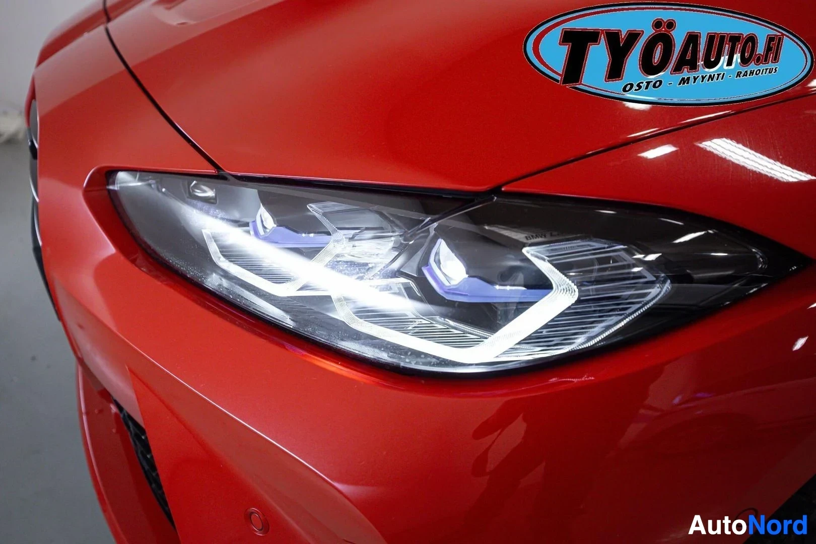 Yksityiskohta: Lähikuva auton punaisesta etuosasta, jossa näkyy LED-ajovalo päällä. Ajovalossa on BMW-logo.