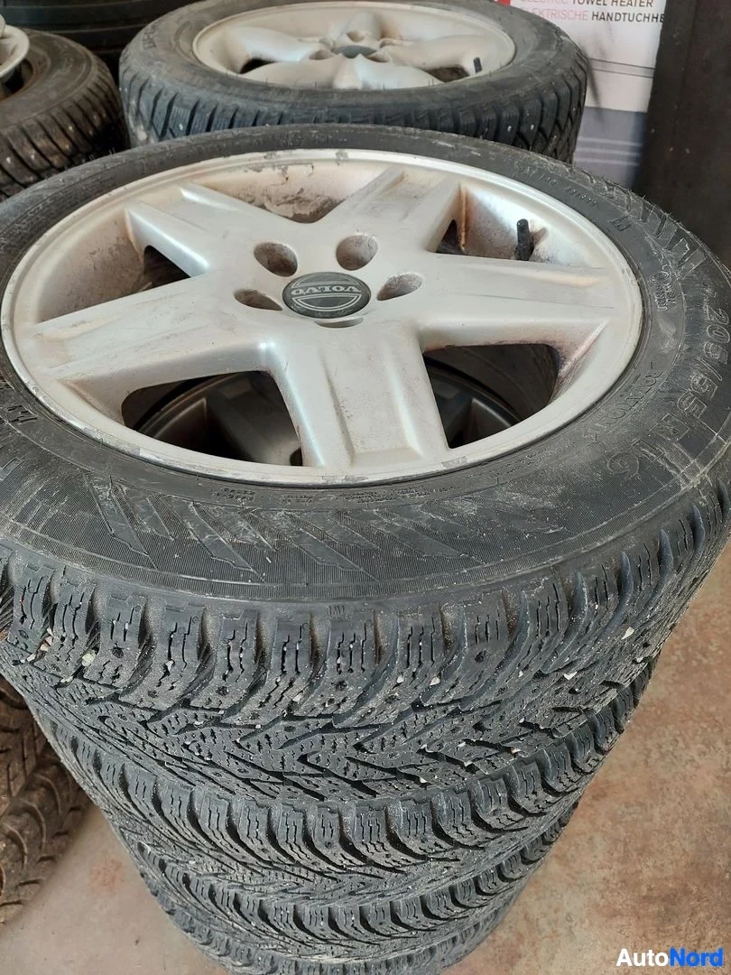 Yksityiskohta: Kuvassa näkyy pino renkaita, joissa on talvirenkaat ja viisisakaraiset kevytmetallivanteet. Volvo-logo näkyy keskikapselissa.