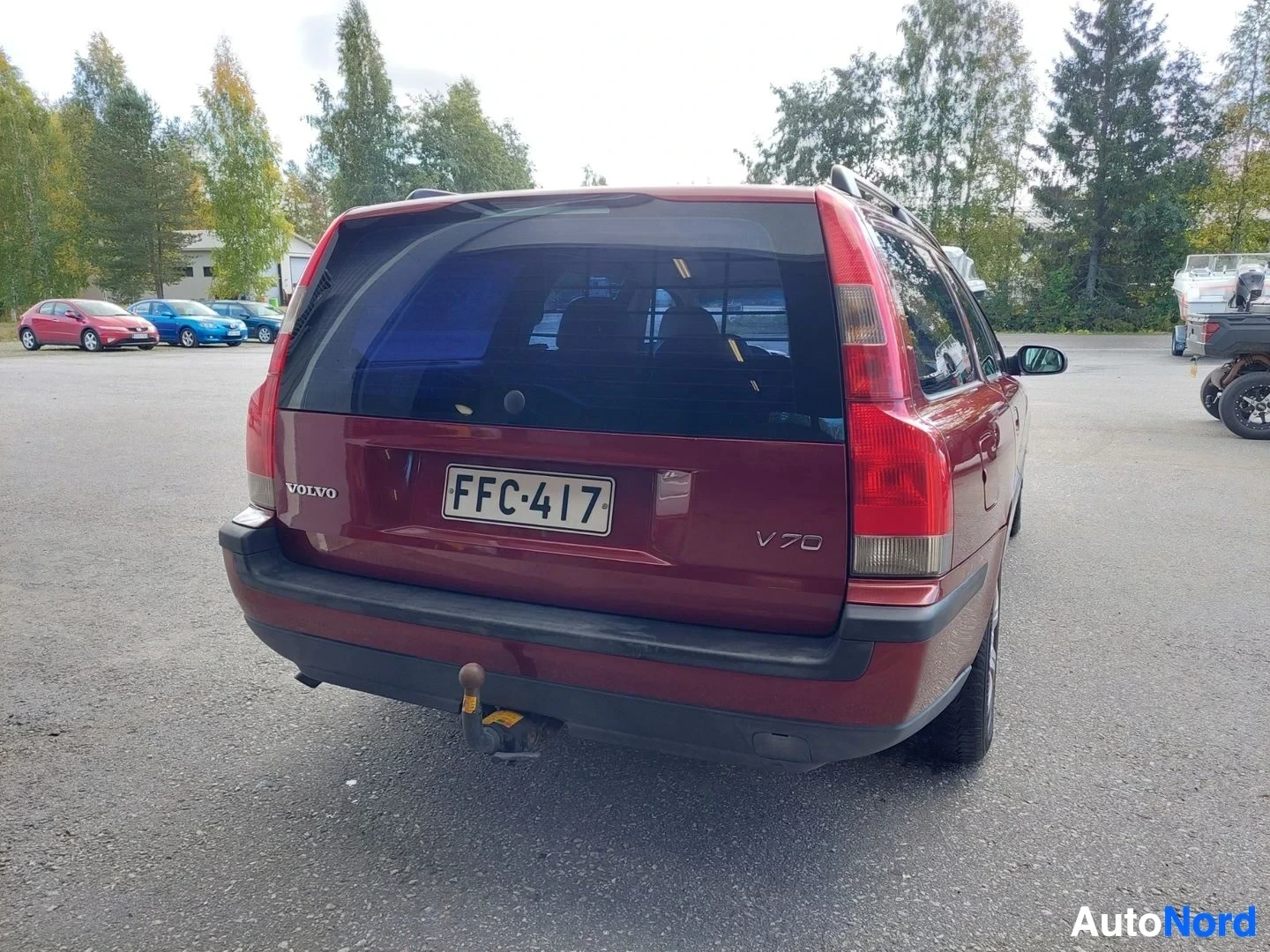 Takaa: Punainen henkilöauto on kuvattu takaa. Takarekisterikilpi ja vetokoukku ovat näkyvissä. Volvo ja V70 logot ovat myös näkyvissä takaluukussa